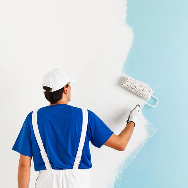 Professional Painter wearing a blue shirt painting a wall white
